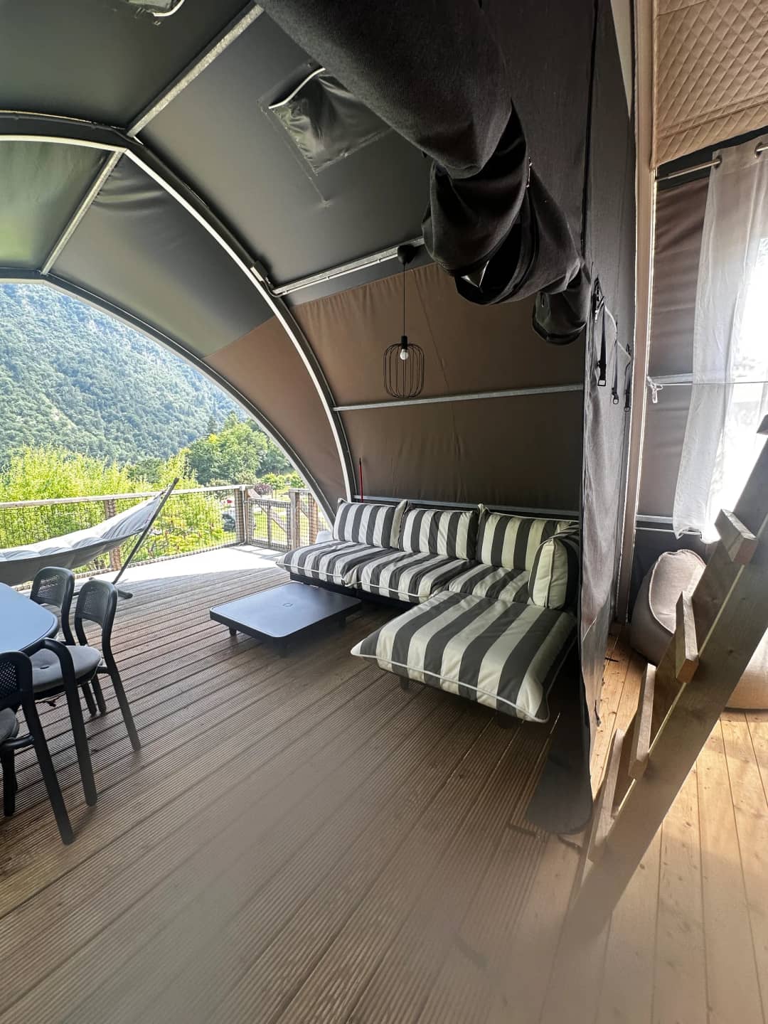 Veranda coperta del Big Oak Lodge XL con divano a strisce, tavolino da salotto e tavolo da pranzo, con vista sulle montagne