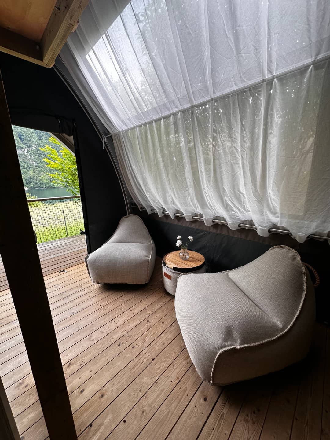 Angolo salotto con pouf sotto la tenda chiara nella Big Oak Lodge XS