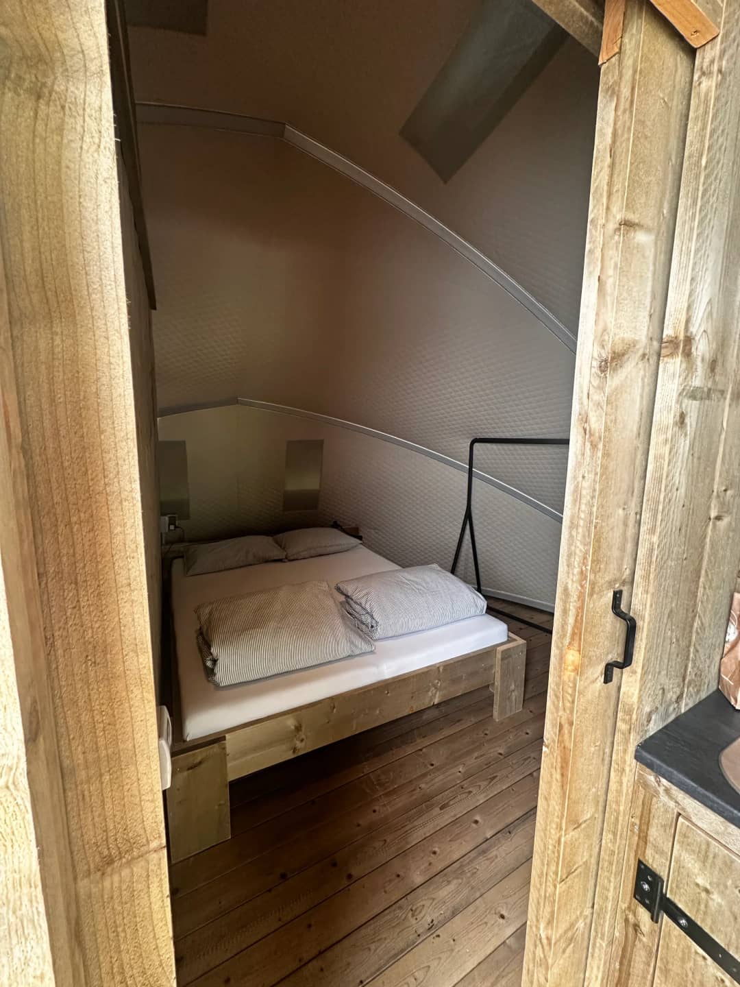 Camera da letto del Big Oak Lodge XL con letto matrimoniale in legno sotto la parete curva, vista dall'ingresso