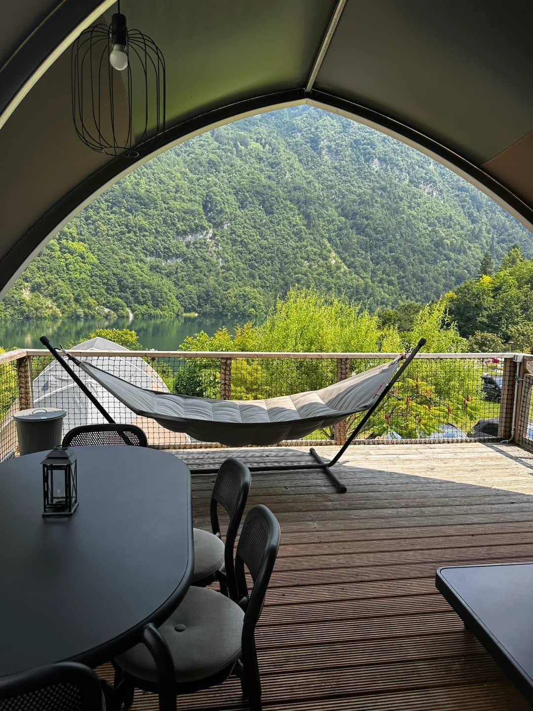 Amaca e tavolo da pranzo con lanterna sulla veranda del Big Oak Lodge XL, con vista sul lago e sulle montagne