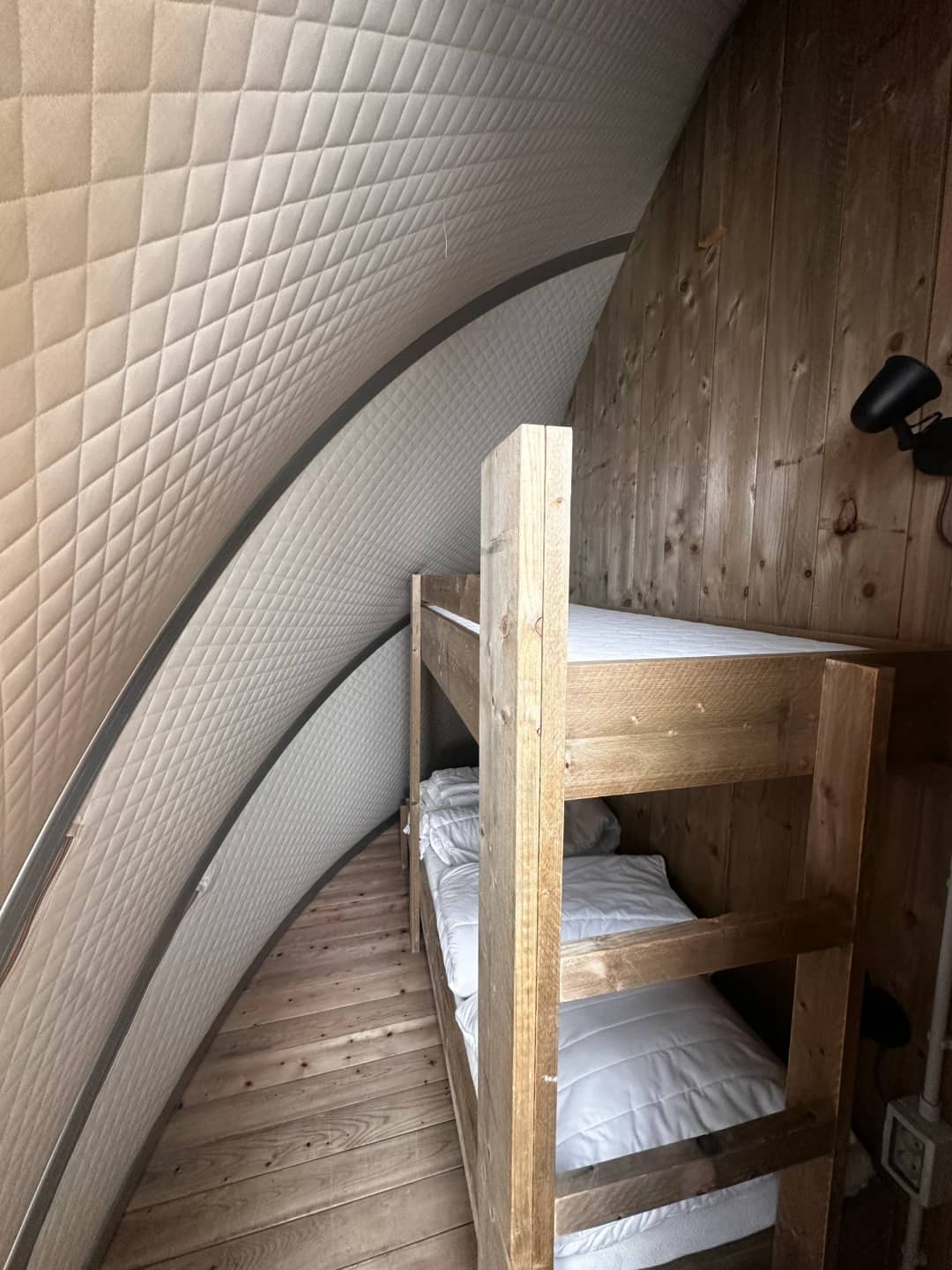 Letto a castello in legno con biancheria da letto bianca sotto la parete imbottita e ricurva del Big Oak Lodge XL